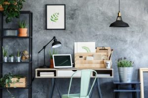 black lamp above lavender in silver bucket on black stool next to desk with laptop in freelancer's room