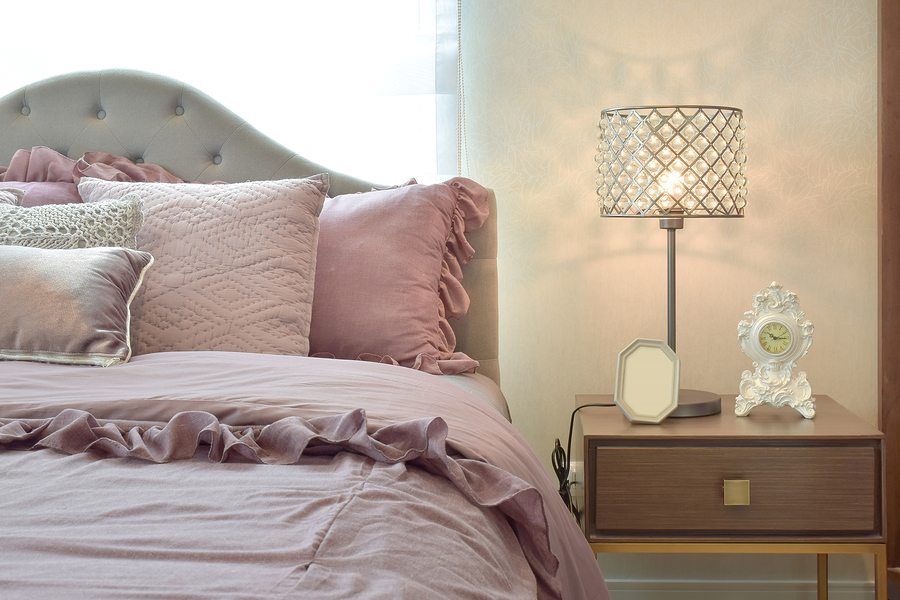 Cozy and classic bedroom interior with pillows and crystal reading lamp on bedside table